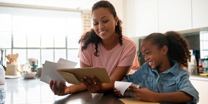 Mother reviewing tax documents next to daughter